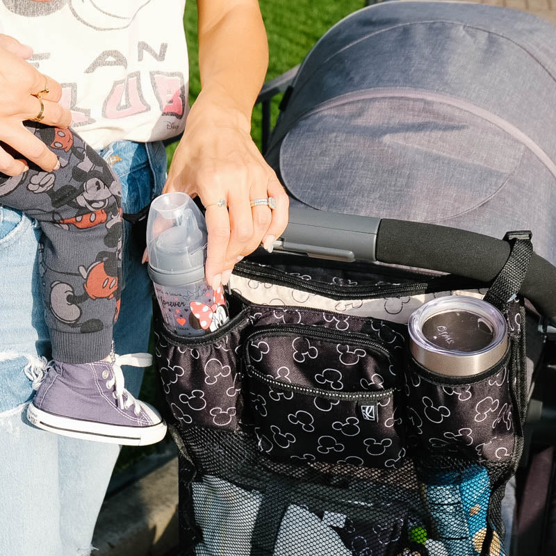 Disney Baby Cups ‘N Cargo Stroller Organizer with woman pulling bottle out of cup holder pocket