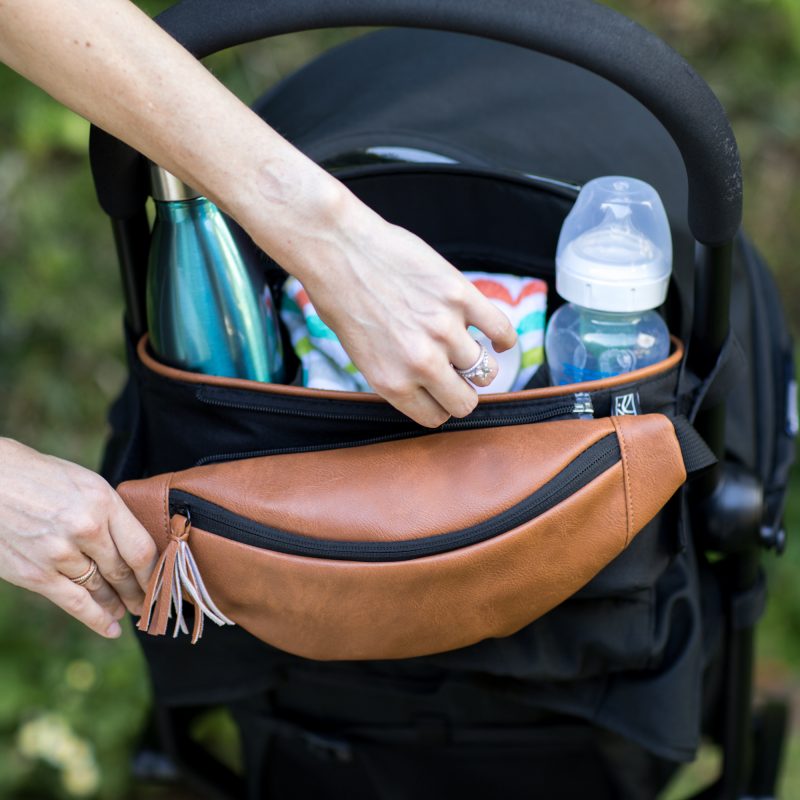 Woman unzipping hip pack from the Stroller Organizer with Hip Pack while hanging on stroller