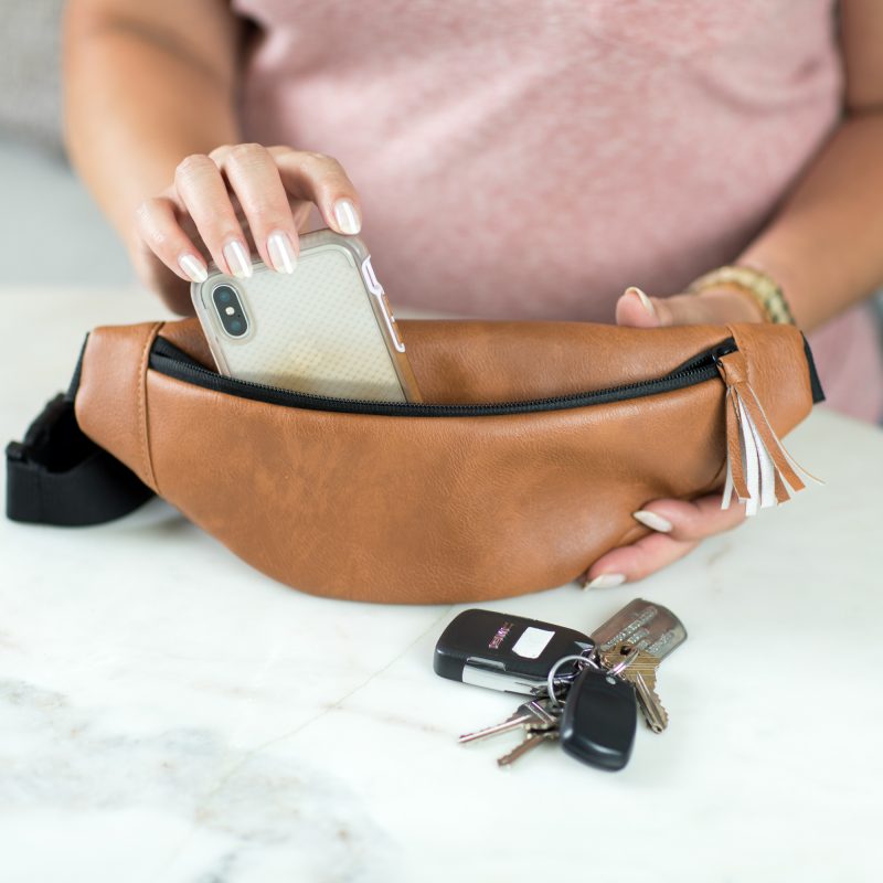 Woman placing phone in the hip pack from the Stroller Organizer with Hip Pack