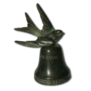 A brass swallow mounted to the top of a 2" x 2" bell. The bell reads "El Camino Real" on the base.