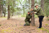 Trail Camera Setup in the Woods: Two Individuals Preparing for Wildlife Observation