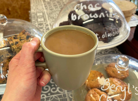 A photo showing a mug of coffee and a selection of cakes