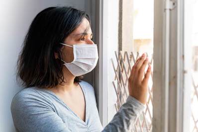 Women looking out window with mask on