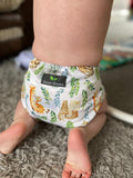 A baby kneels wearing a cute nappy