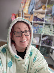 Green Cheeks owner wearing turtle recall oodie hooded blanket while working from home