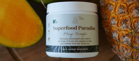 superfood paradise bottle next to some mango and pineapple