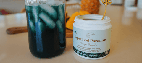 Superfood Paradise bottle next to a drink made with the product