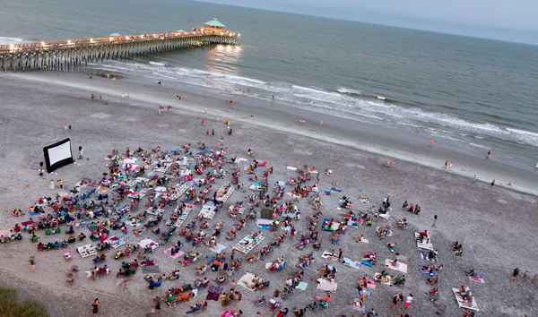 People on blankets watching open air cinema by the beach