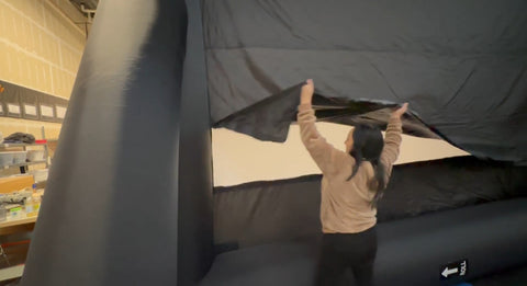 A lady removing an Open Air Cinema rear blackout backdrop from the left bottom side