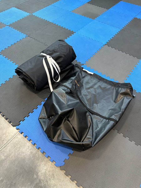 an Open Air cinema outdoor screen neatly folded and an Open Air Cinema storage bags both kept on the floor