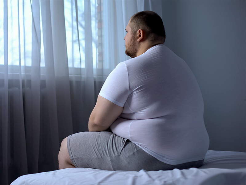 Overweight man sat on a bed