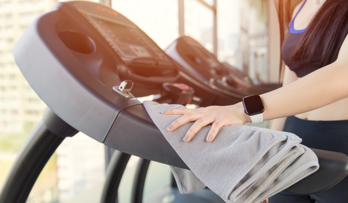 woman wiping down treadmill after using it