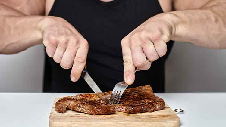 bodybuilder eats a steak