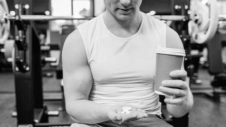 Closeup of sporty muscular man arms showing sports and fitness supplements