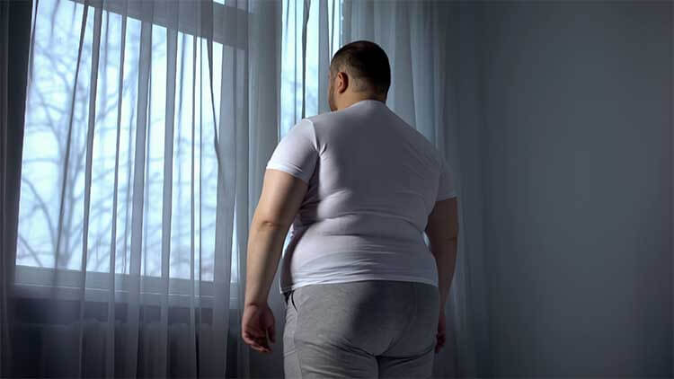 Fat man looking out through window, depressed introvert ashamed of obese body