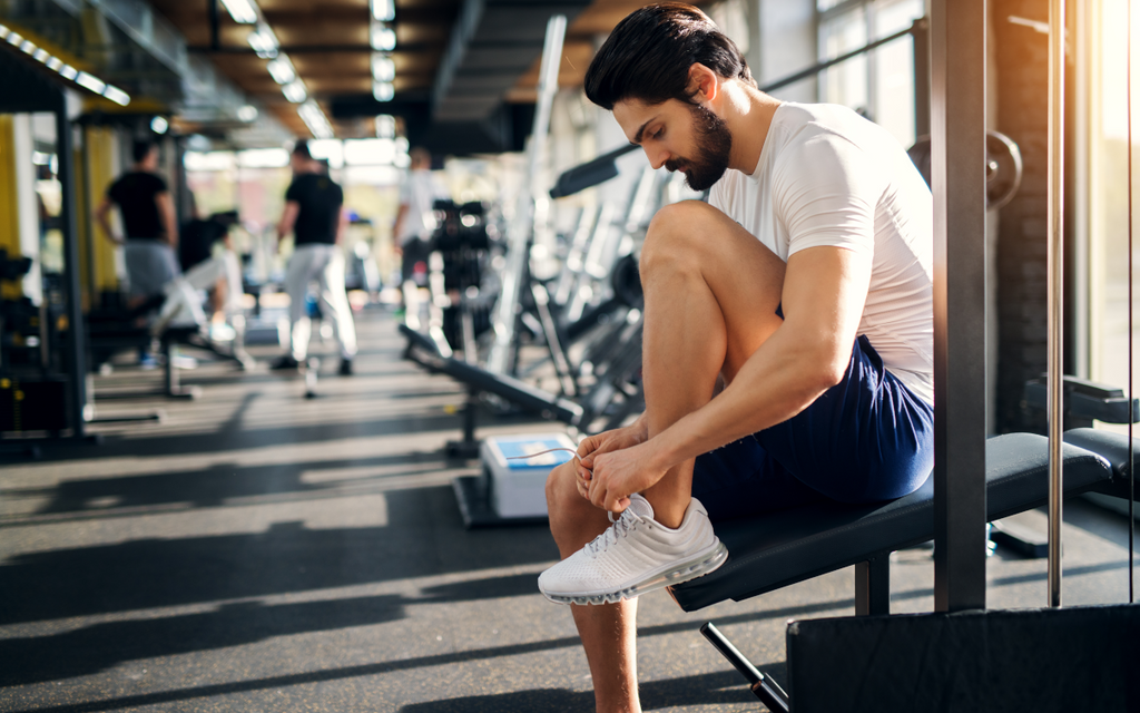 Man tying shoe in gym