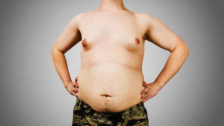Torso of young fat man with hands on belt on gray background.