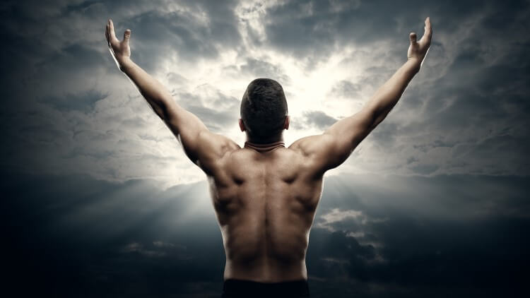 Athletic man with open arms pointing to sunrise in clouds