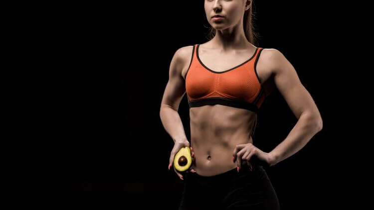 Athletic woman holding hips and avocado