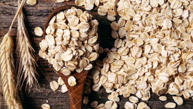 Oats on wooden spoon at on wooden table