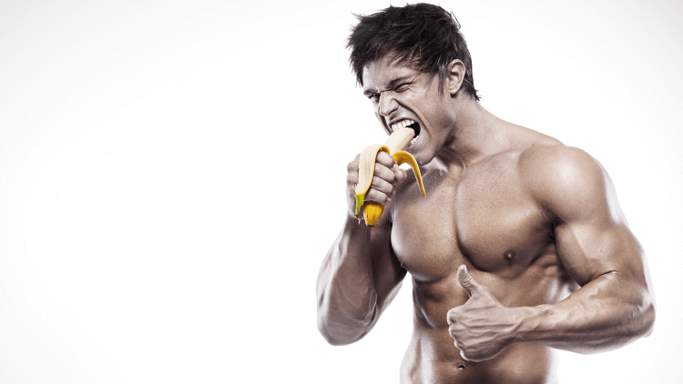 Muscular man giving thumbs up eating banana