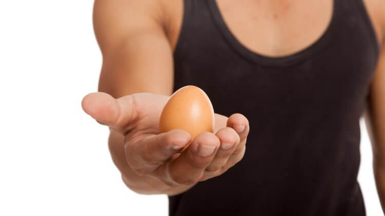 Man holding out egg towards camera