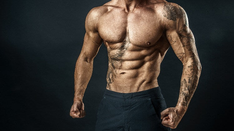 Muscular tattooed man clenching fists black background