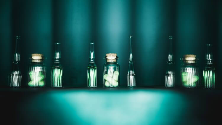 Pills in glass containers on blue background