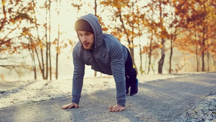 Young man doing push ups on cold autumn morning