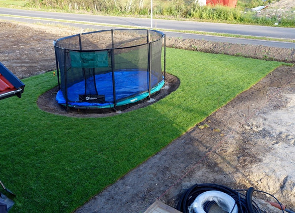 Gräsmattan runt nedgrävda trampolinen