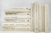 Foil lettered beige decorator books. Color-coded book stack by the shelf foot
