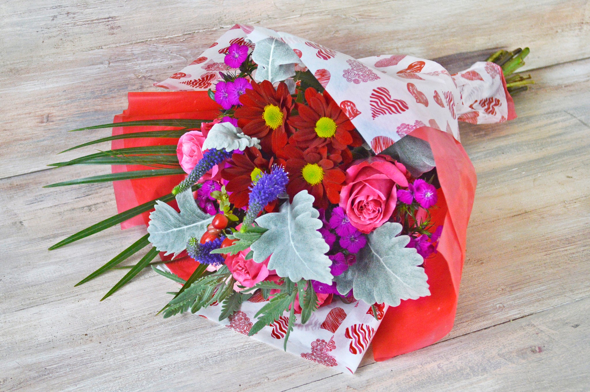 Floral bouquet designed to celebrate love, composed of premium roses, daisies, veronica, dianthus and foliage.
