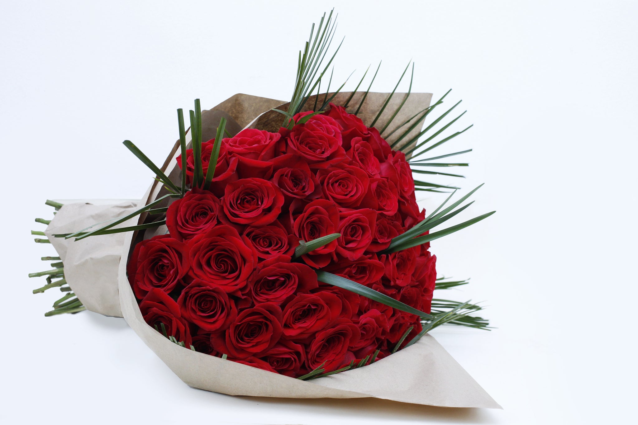 Unforgettable 50 Rose Hand-tied Side - red roses , palm leaves , steel grass, bouquet. Side shot of 50 red roses hand tied.