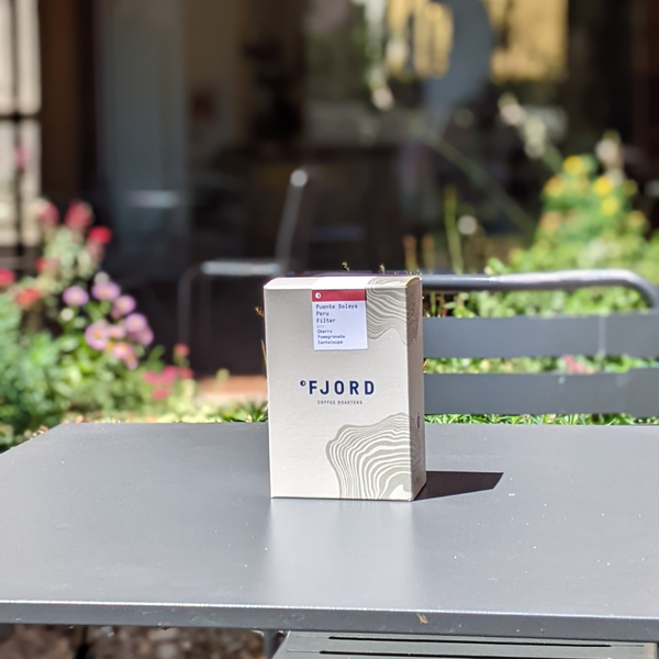 A box of Fjord coffee sits atop a sunlit table.