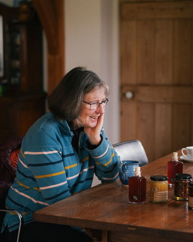 A lady sitting at her kitchen table with honey and vinegar