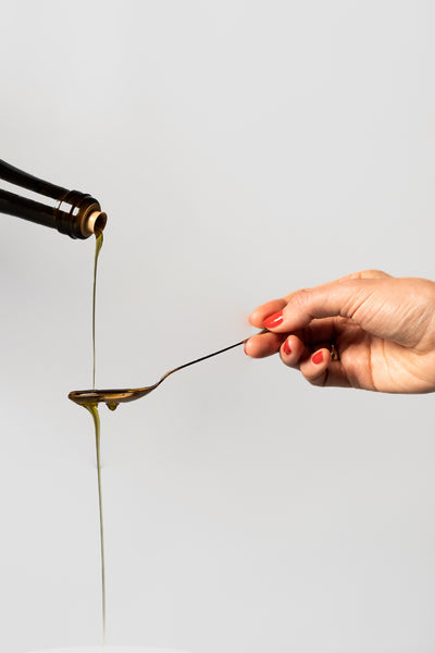 Pouring a spoon of extra virgin olive oil 