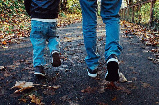 Image of father and son walking down a leaf strewn lane