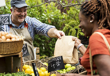 Image of customer buying vegetables at an outdoor market