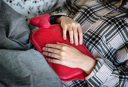 Image of a woman with a hot water bottle on her stomach
