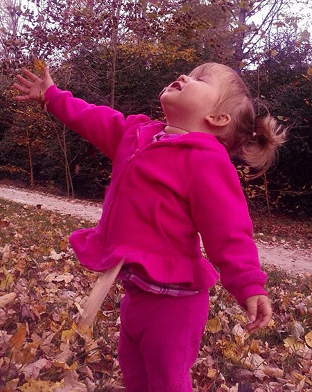image of child playing in the autumn leaves