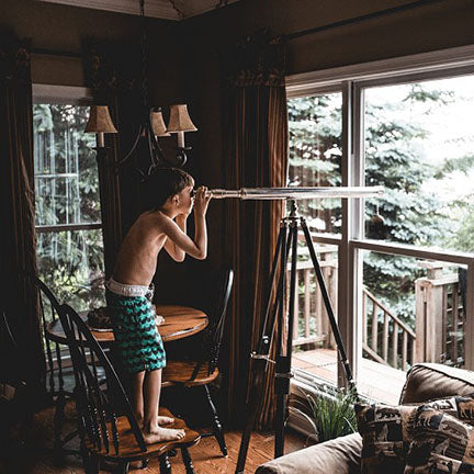 Image of young boy watching the world go by through his telescope