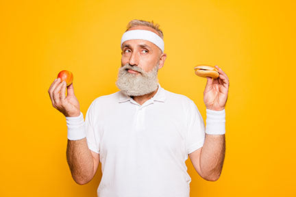 Image of man holding an apple and a donut trying to decide which to eat