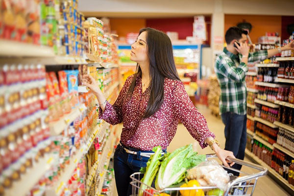 Image of a young woman carefully choosing her purchases in a grocery store