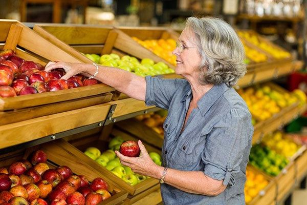 Image of a middle-aged woman carefully selecting produce