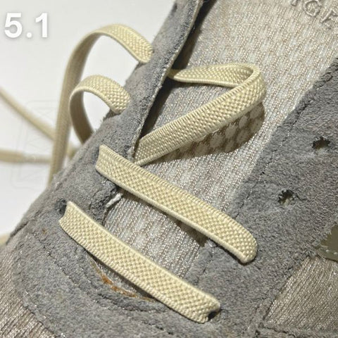 Geperforeerde grijze schoen met beige veters klaar om te dragen na het volgen van een straight-bar rijginstructie.