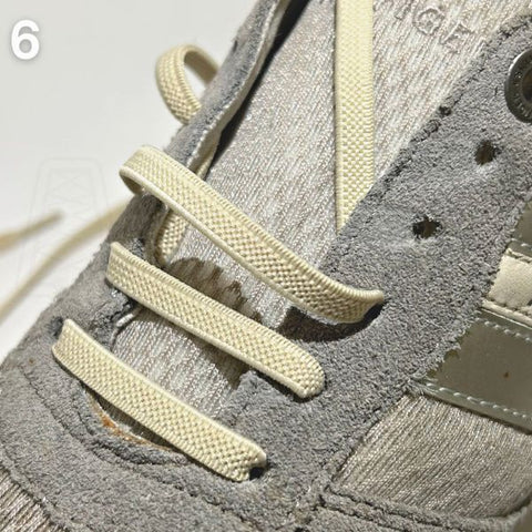 Grijze schoen voorzien van de straight-bar rijgtechniek, een van de nette methodes om veters in schoenen te doen.