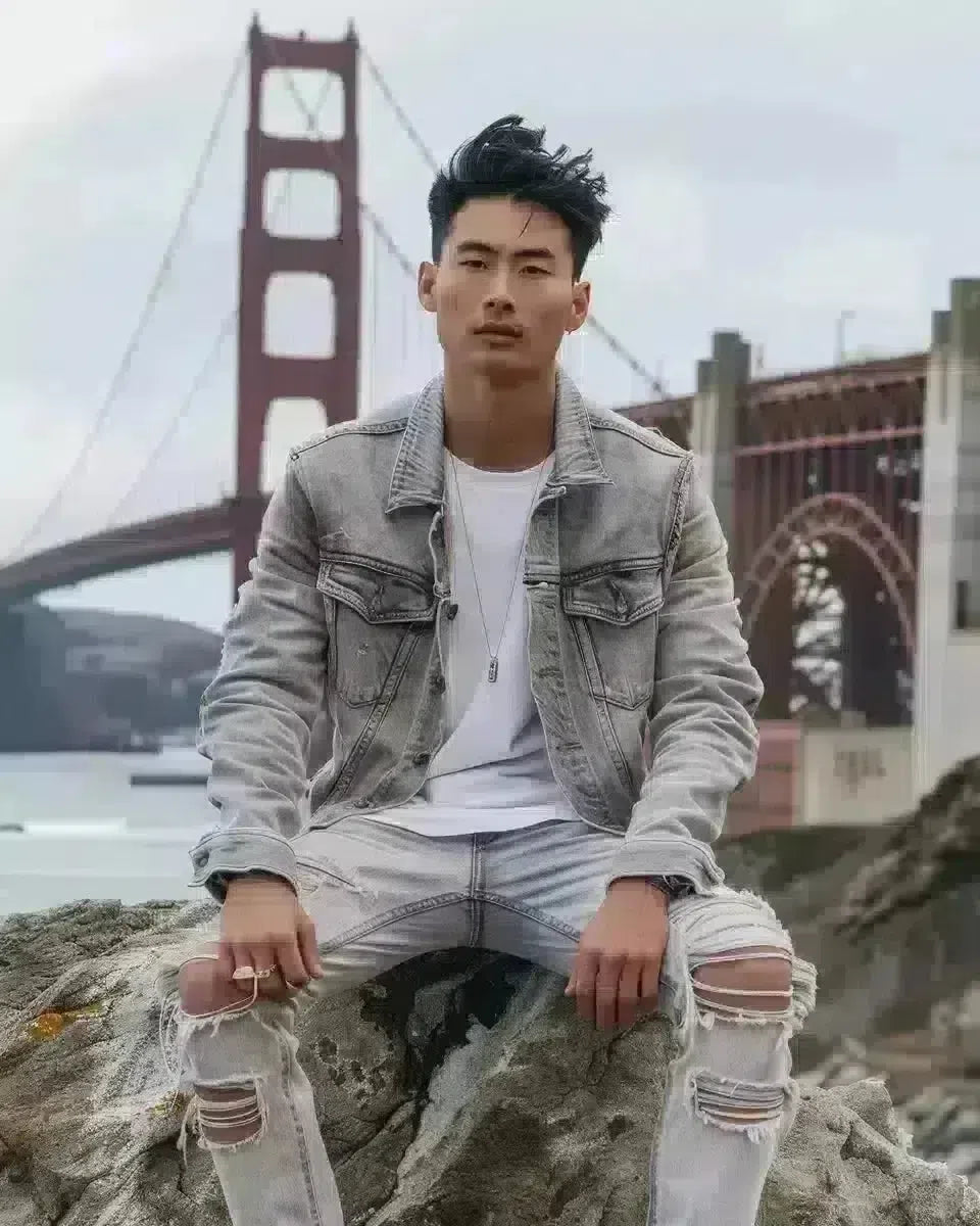 Asian male model in grey ripped jeans, posing by Golden Gate Bridge. Spring season.