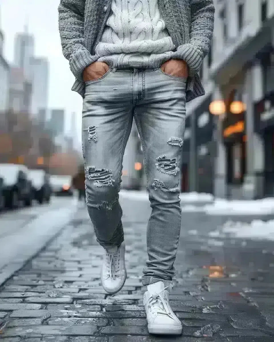 Urban man in grey ripped denim jeans, outdoor city background, local elements. Spring season.