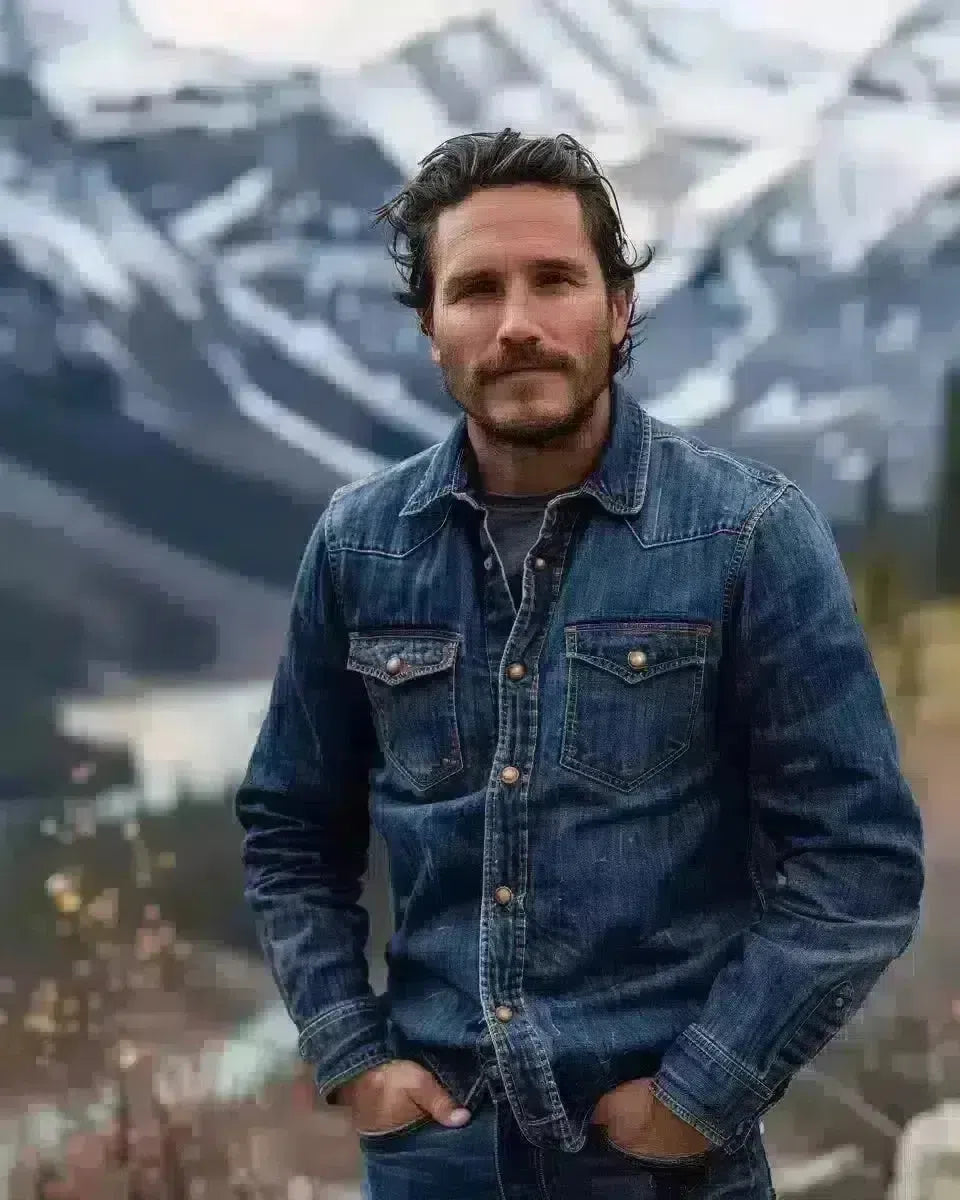 Man in raw denim jeans, Alberta Rockies backdrop, embodying rugged durability. Spring season.