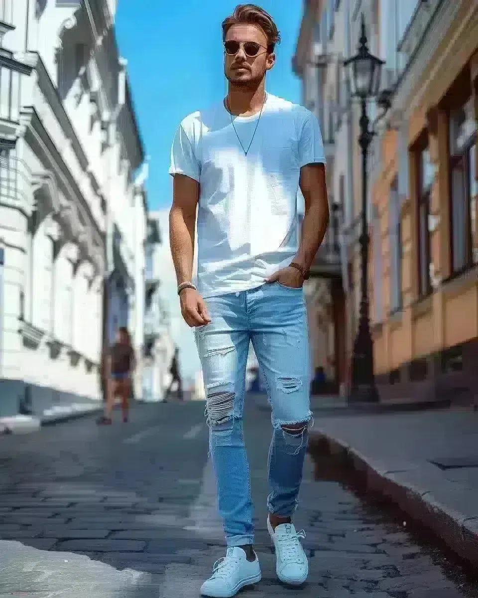 Stylish man in vibrant blue ripped jeans, outdoor urban setting. Spring season.
